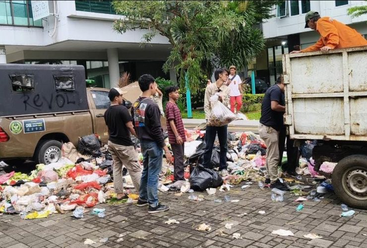 Pemuda Tangerang Selatan membersihkan tumpukan sampah sisa demo mahasiswa di area Kantor Wali Kota Tangsel menggunakan truk pengangkut sampah.