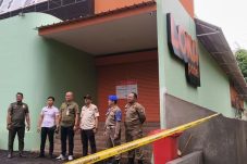 Petugas Satpol PP Tangsel dan PPNS berdiri di depan bangunan Loka Padel Tandon Ciater yang disegel karena belum memiliki izin PBG.