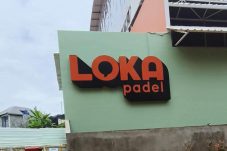 Tampak depan bangunan Loka Padel di Jalan Tandon Ciater, Serpong, Tangerang Selatan, dengan papan nama berwarna oranye dan hitam menempel di dinding hijau.