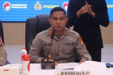 Kapolres Tangerang Selatan mengenakan seragam Polri saat memberikan keterangan pers di ruang konferensi, dengan papan nama “Kapolres” di meja dan petugas bahasa isyarat di belakangnya.