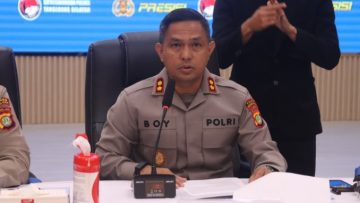 Kapolres Tangerang Selatan mengenakan seragam Polri saat memberikan keterangan pers di ruang konferensi, dengan papan nama “Kapolres” di meja dan petugas bahasa isyarat di belakangnya.